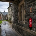 Fire alarm call point and signage in a school corridor in Cumbria