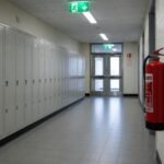 Fire alarm call point on the wall of a school corridor in Cumbria