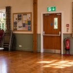 Fire door with self-closer and signage inside a Cumbria community hall