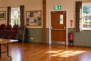 Fire door with self-closer and signage inside a Cumbria community hall